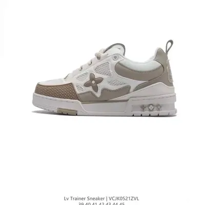 A white and taupe low-top trainer with a monogram flower panel on the side and a thick white sole, photographed on a plain background.